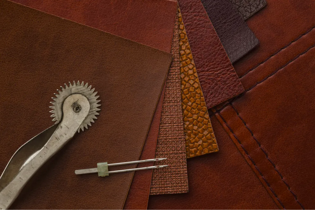 Leather hides, cutting tools and a stitching pony on a workbench